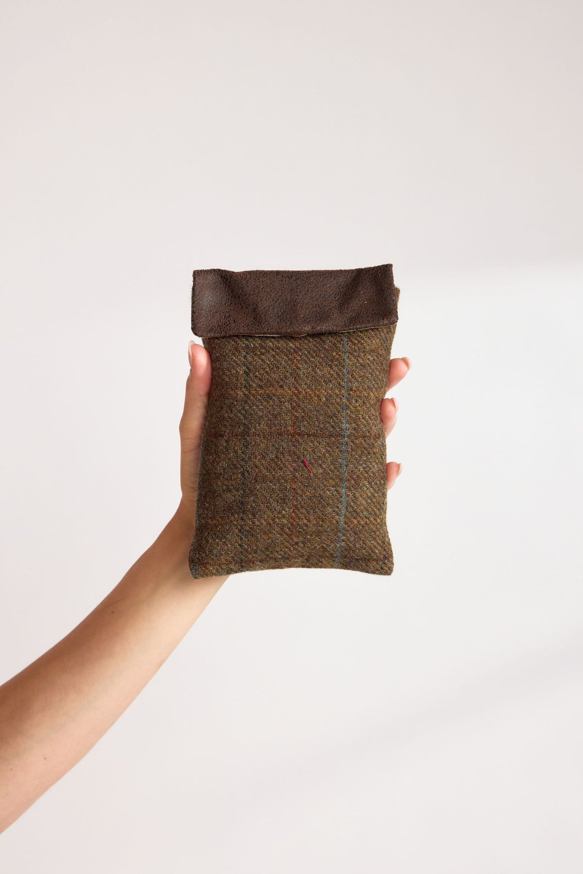 Chocolate brown Yorkshire tweed phone pouch with a dark brown faux leather flap, held in hand