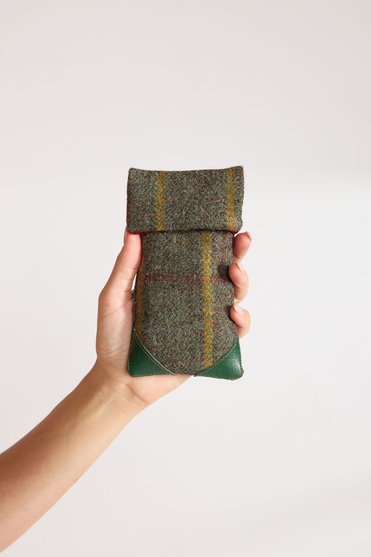 Moss green Yorkshire tweed glasses case with green leather corners, held in hand