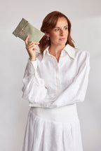 Mint green herringbone tweed phone pouch with printed lining, held in hand
Model Emma in a white linen shirt and skirt holding the Mint herringbone tweed phone pouch