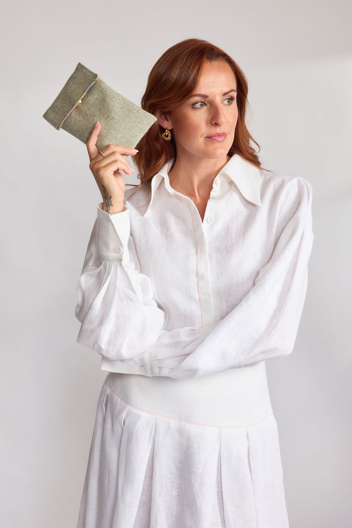 Mint green herringbone tweed phone pouch with printed lining, held in hand
Model Emma in a white linen shirt and skirt holding the Mint herringbone tweed phone pouch